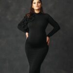 A beautiful turtleneck dress with a decorative ruffle on the shoulder.